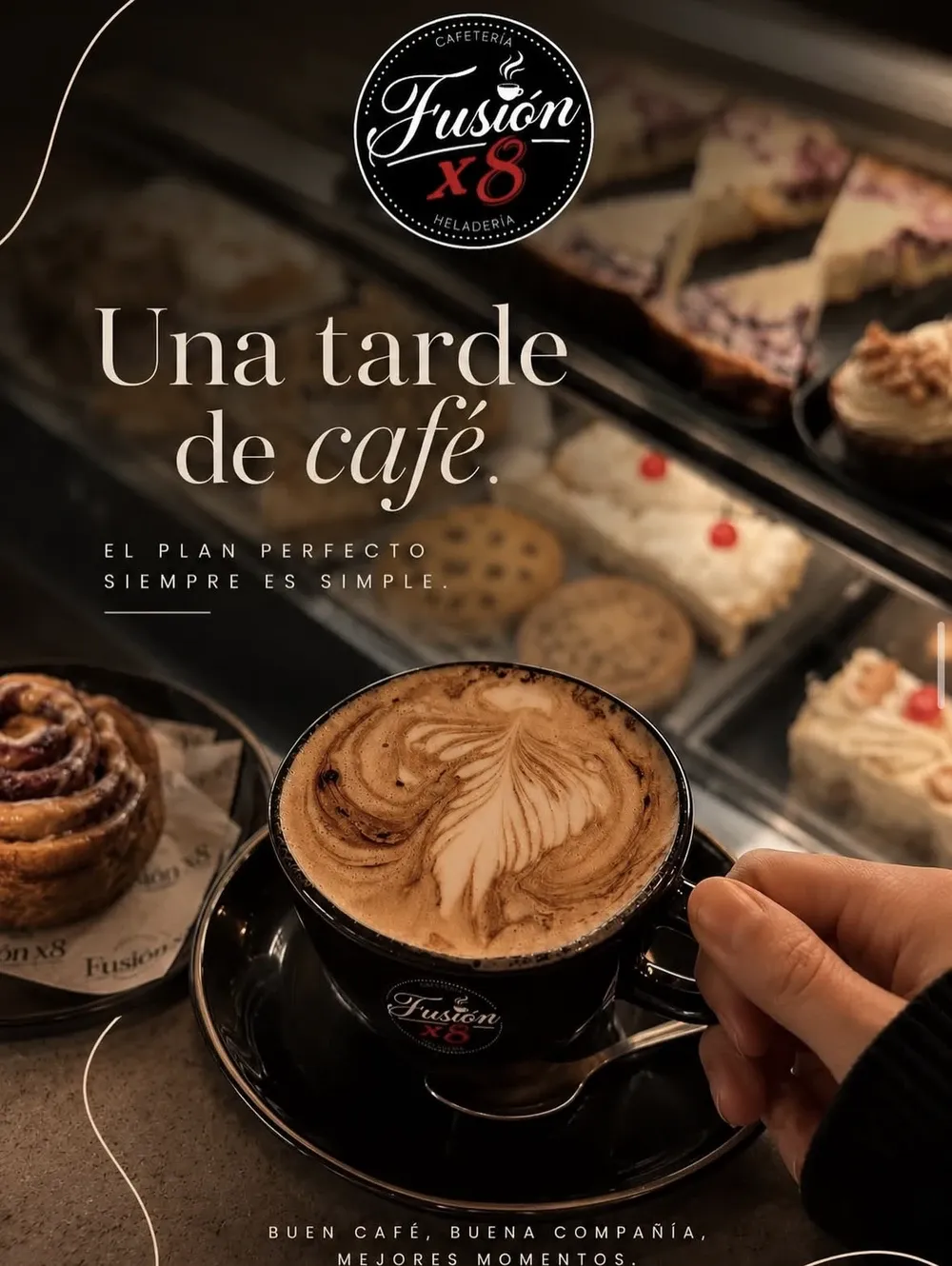 Una taza de café con arte latte junto a la vitrina de pastelería.